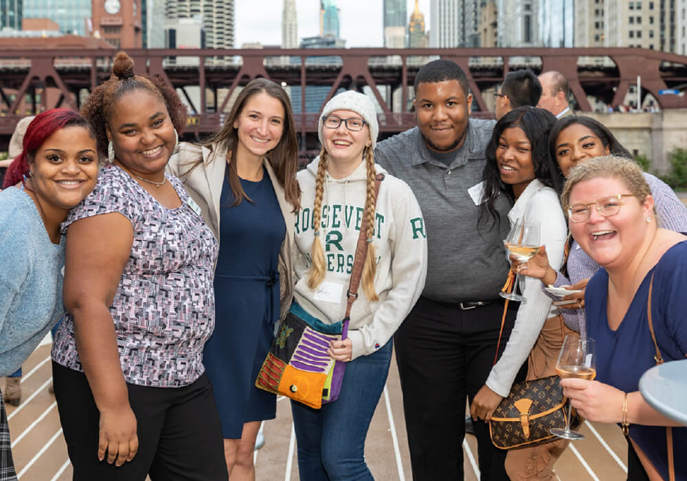 Header image: a diverse group from The Young Professionals Association from Roosevelt University in a group photo, enjoying downtown Chicago